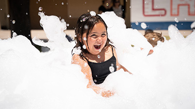 Summer Ed camp student playing in large amount of foam bubbles Summer Ed camp student playing in large amount of foam bubbles