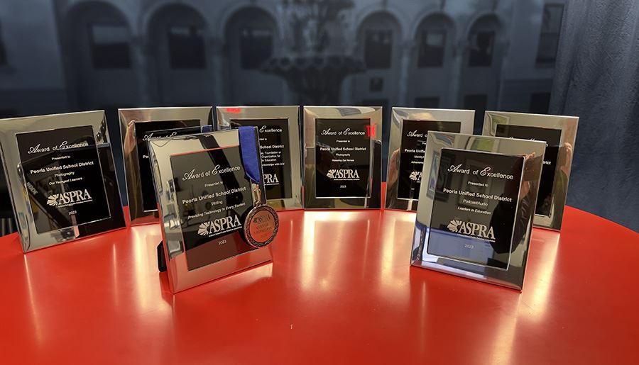  9 framed ASPRA awards arranged on a red table. 