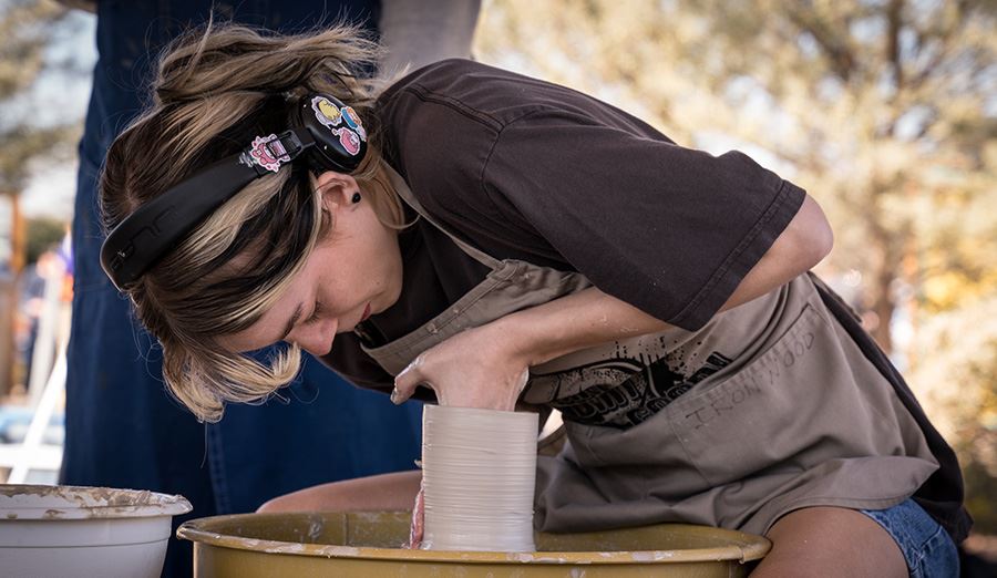  Female student works with clay on a pottery wheel