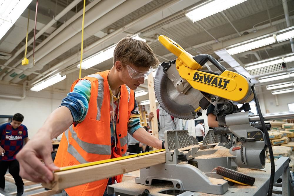 Construction student using tape measure near table saw