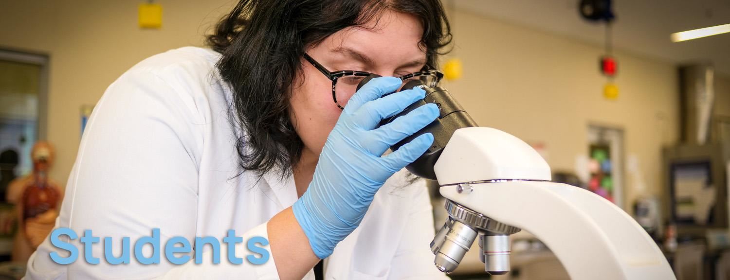 Student looks through microscope. Text: Students