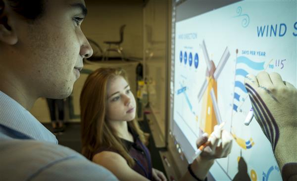 High school students writing on interactive whiteboard