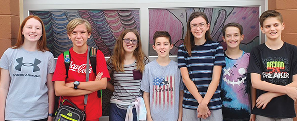 several middle school students pose in front of office